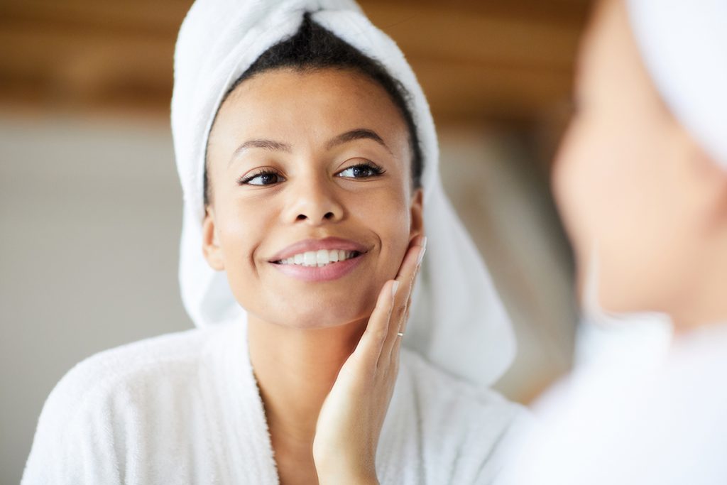 Woman touching face in mirror